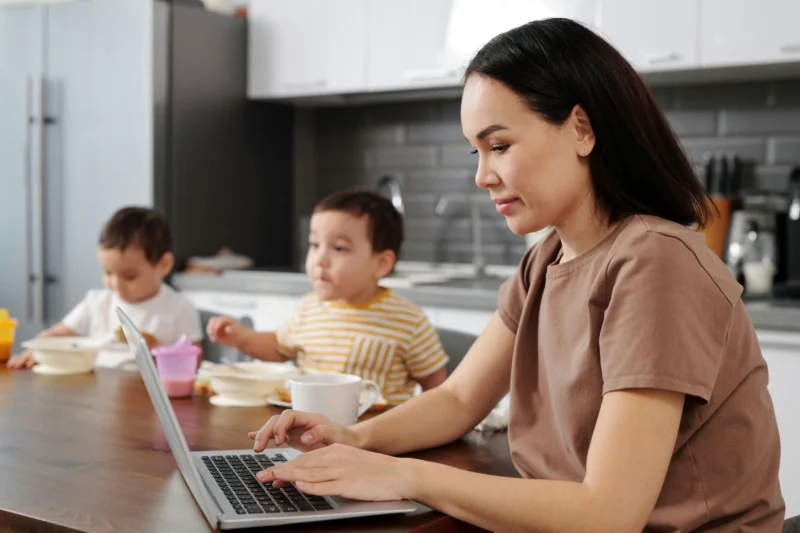 Mulher trabalhando como Closer Digital com filhos ao fundo