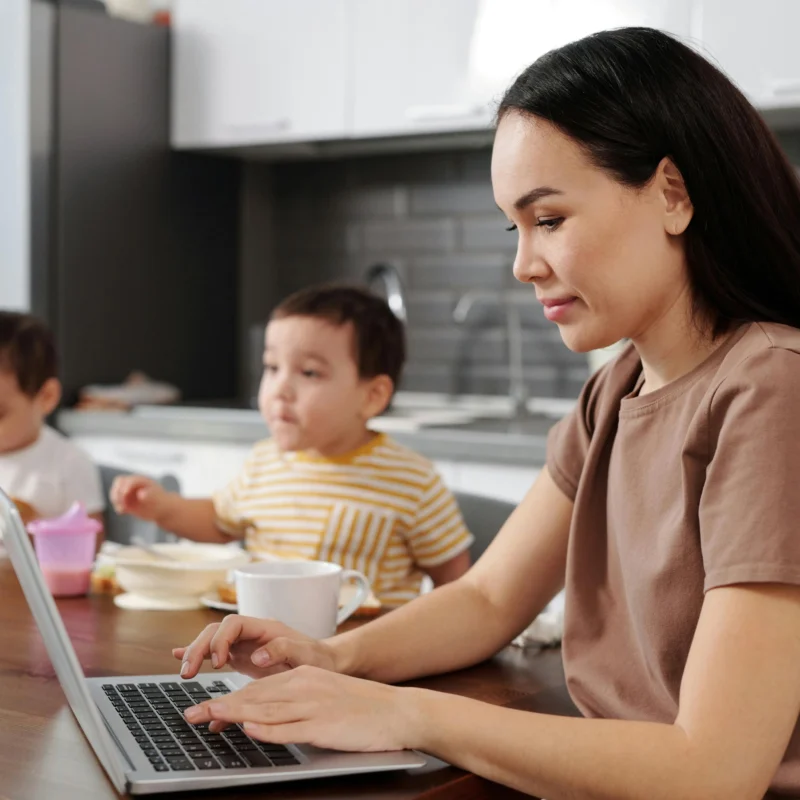 Mulher trabalhando como Closer Digital com filhos ao fundo